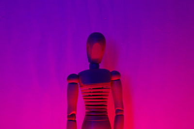 Close-up of wooden figurine against purple wall