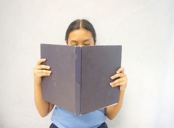 Girl reading book against white background
