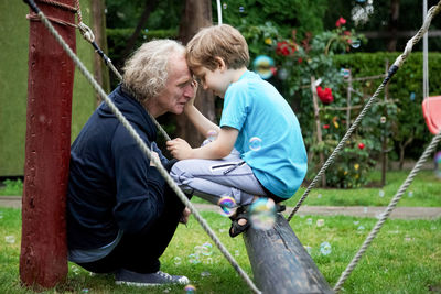 Mature man and grandson crouching in playground