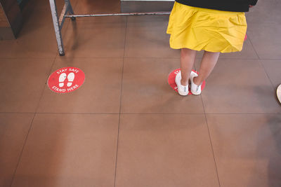 Low section of woman with umbrella on tiled floor