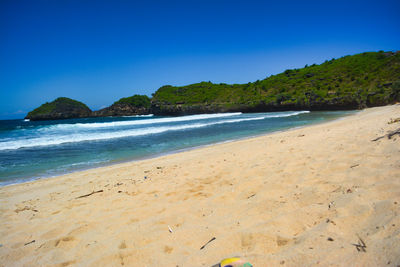 Scenic view of beach against clear blue sky