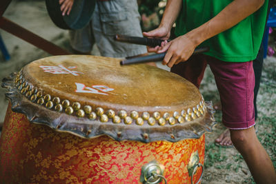 Midsection of man banging drum outdoors