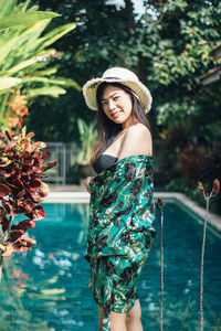 Portrait of woman wearing hat standing at poolside