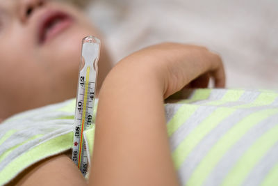 Close-up of boy lying with thermometer