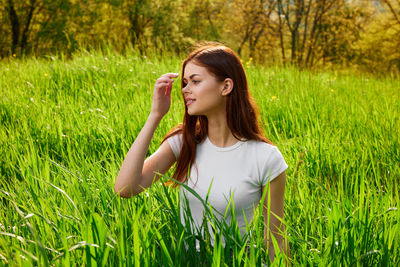 Portrait of young woman standing on grassy field