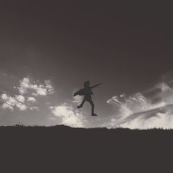 Low angle view of silhouette person jumping against sky