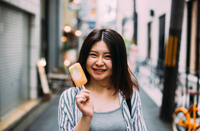 Portrait of woman eating food in city
