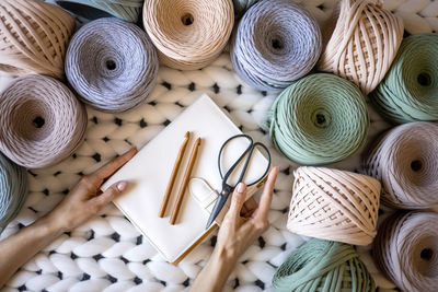 Woman holding hand tools and diary amidst multi colored threads