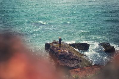 High angle view of man standing on rock in sea