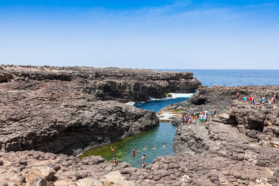 High angle view of people enjoying swimming in sea against sky