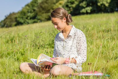 Portrait of beautiful young student reading a book in the school park