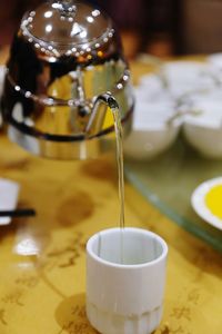 Close-up of tea from pot in cup on table