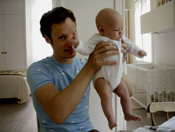 Father lifting baby girl at home