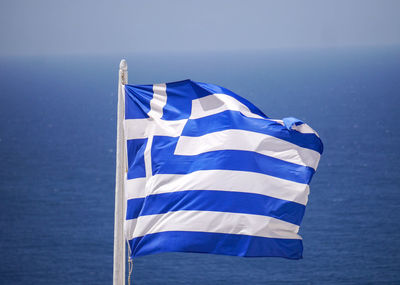 Close-up of greek flag against seascape