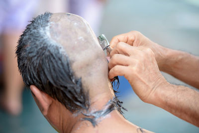 Cropped hands of barber shaving head of man