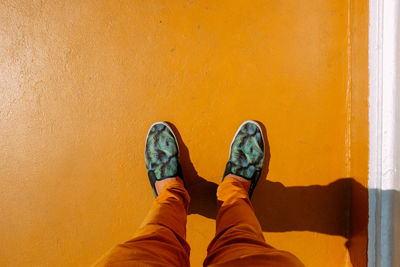 Low section of man standing against yellow ground