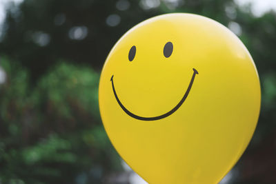 Close-up of smiley on yellow balloon outdoors