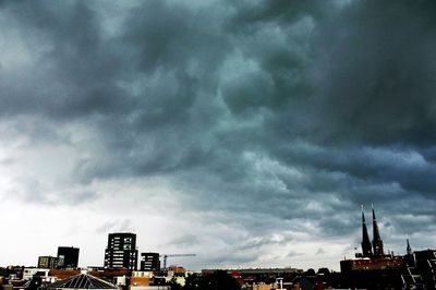 Low angle view of cityscape against cloudy sky