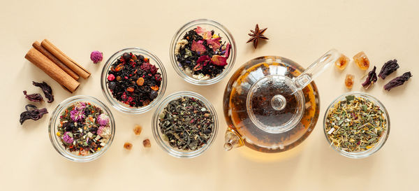 A set of different types of herbal tea next to the kettle   on a beige background.