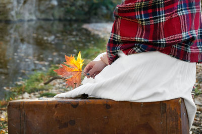 Low section of woman holding autumn leaf