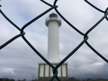 View of metal fence against cloudy sky