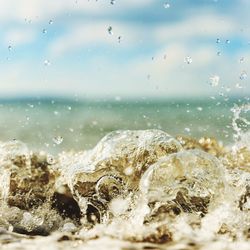 Close-up of splashing water in sea against sky