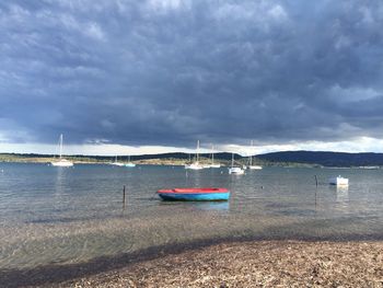 Boats in sea against cloudy sky