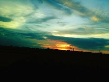 Silhouette landscape against dramatic sky during sunset