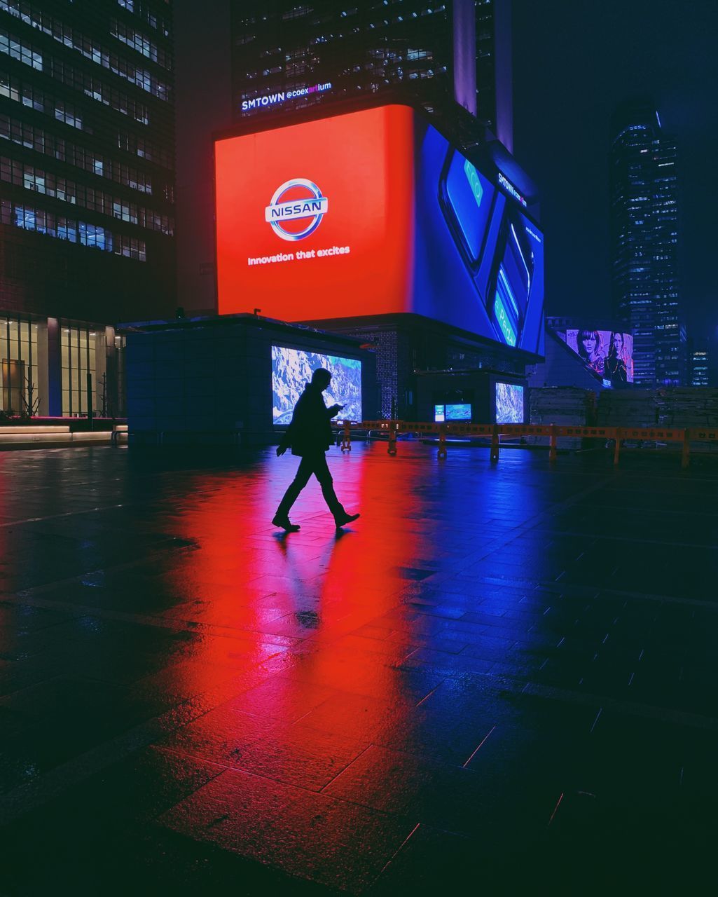 MAN WALKING ON ILLUMINATED STREET AT NIGHT