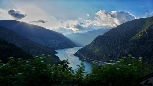 Scenic view of river and mountains against sky