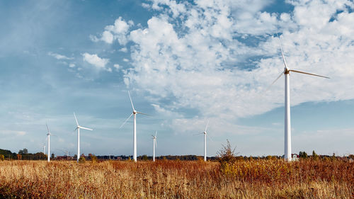 Wind turbines on field against sky