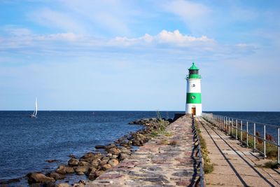 Lighthouse by sea against sky