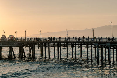 Silhouette pier on beach against sky during sunset