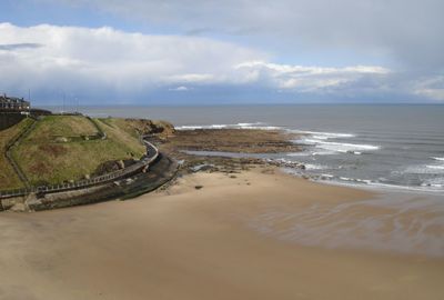 Scenic view of beach against cloudy sky