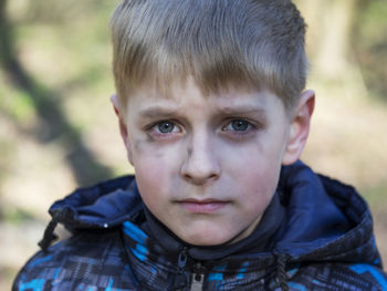 Close-up portrait of serious boy with soot smear on face