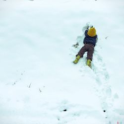 High angle view of child playing with snow on field