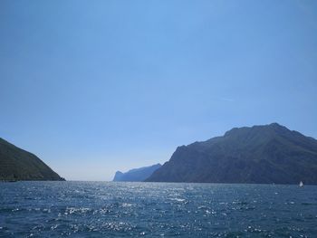 Scenic view of sea and mountains against clear blue sky