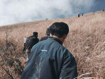 Rear view of man standing on field against sky