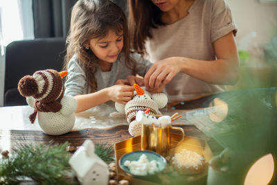 Mother and daughter sitting on table