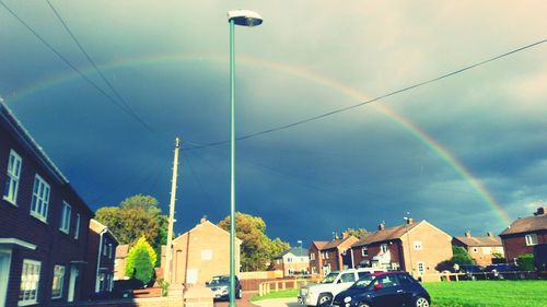 Rainbow over buildings in city against sky