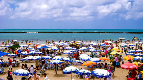 Group of people at beach against sky