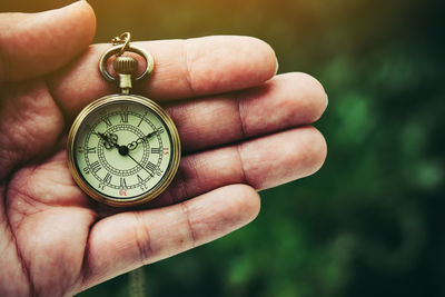 Close-up of hand holding pocket watch outdoors