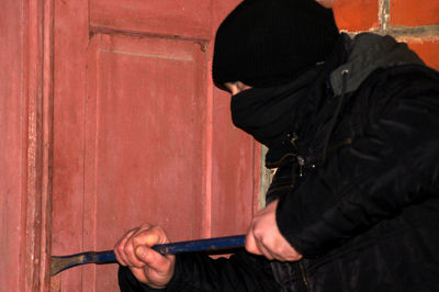 Side view of man holding hands against wall