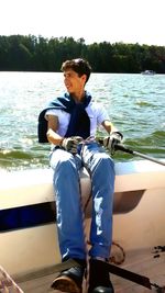 Man sitting in boat against sky