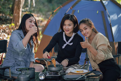 Young women and her friend cooking fried egg on stove for dinner at outdoor together