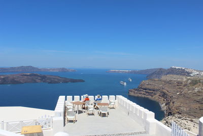 Rear view of senior women sitting on terrace by sea against sky at santorini