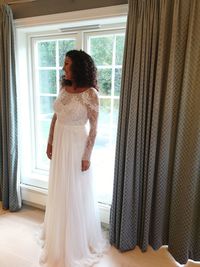 Smiling bride standing on floor by window at home