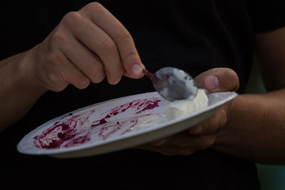 Midsection of man eating ice cream served in plate