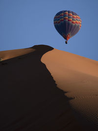 Low angle view of hot air balloons in desert against clear blue sky