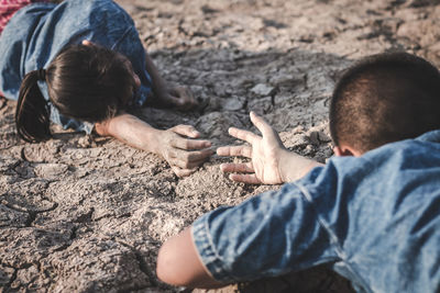 Siblings lying on cracked land